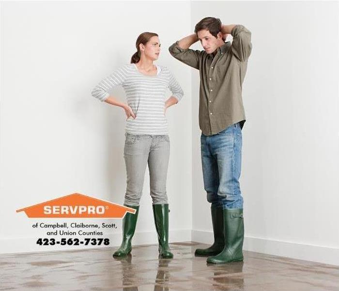 man and women in rain boots standing in standing water 